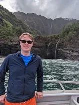 Matt on a boat in front of the Nāpali cost in Kauai, HI
