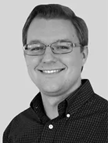 headshot of smiling man wearing glasses