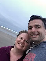 Peter and partner smiling on windy beach