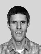 a black and white headshot photo of Travis